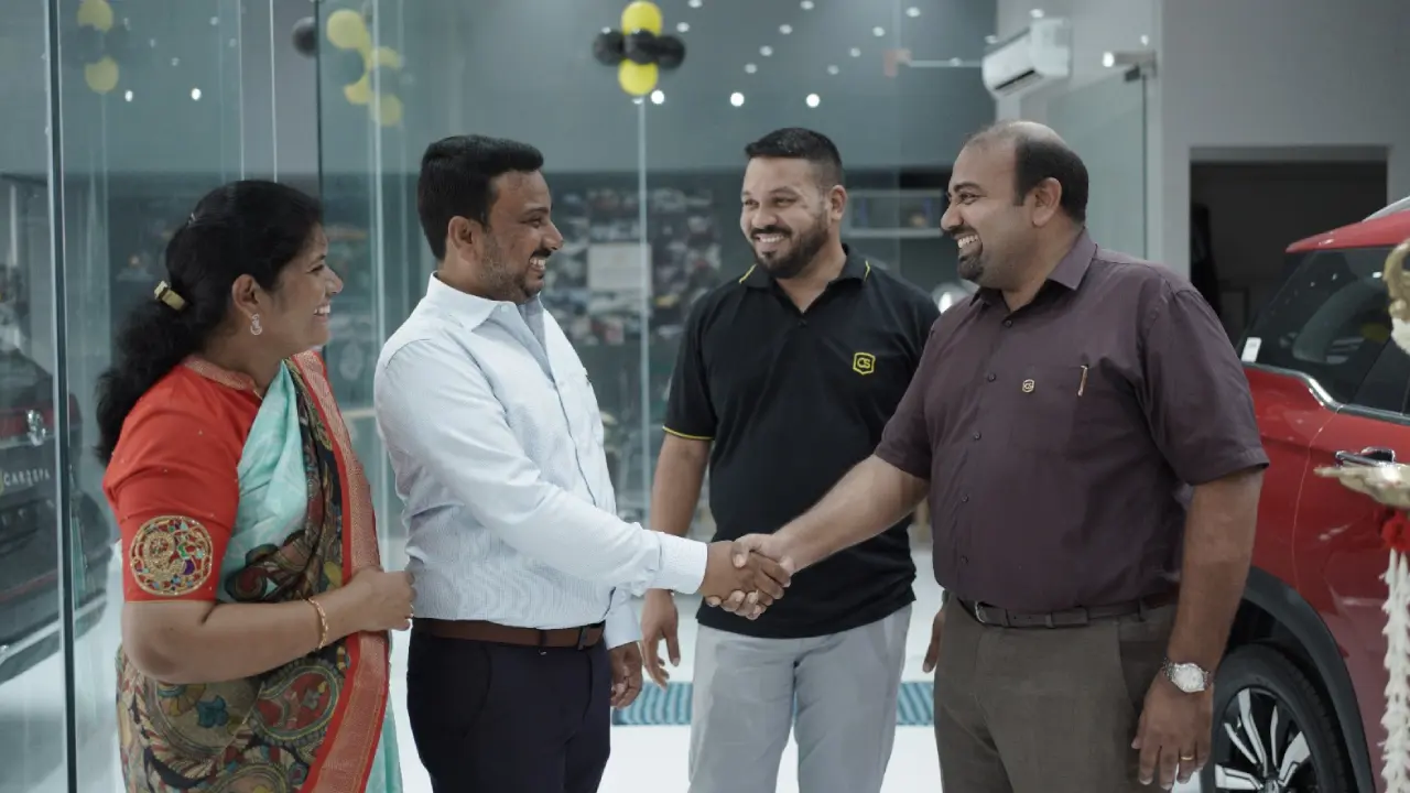 A group of happy people shaking hands with each other in front of a car detailing franchise