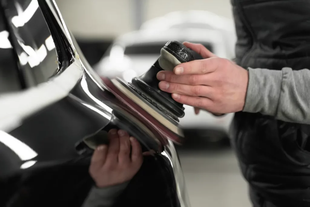 a man polishing a part of black coloured car