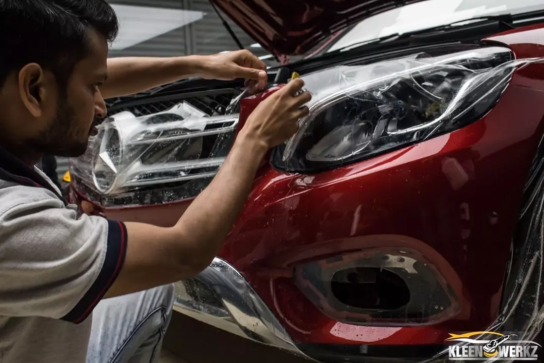 A car detailer applying paint protection film on a car