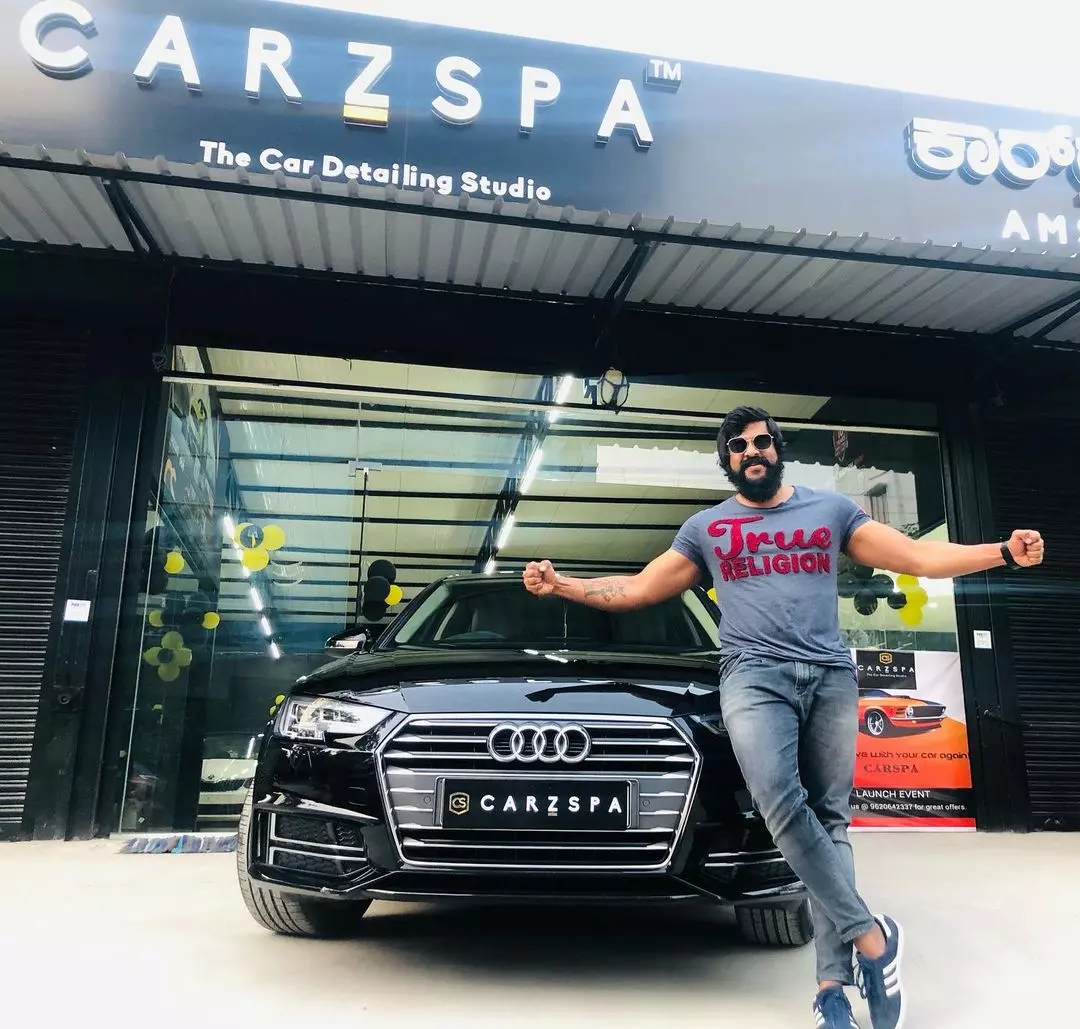 An Indian man standing in front of his car outside a car detailing studio