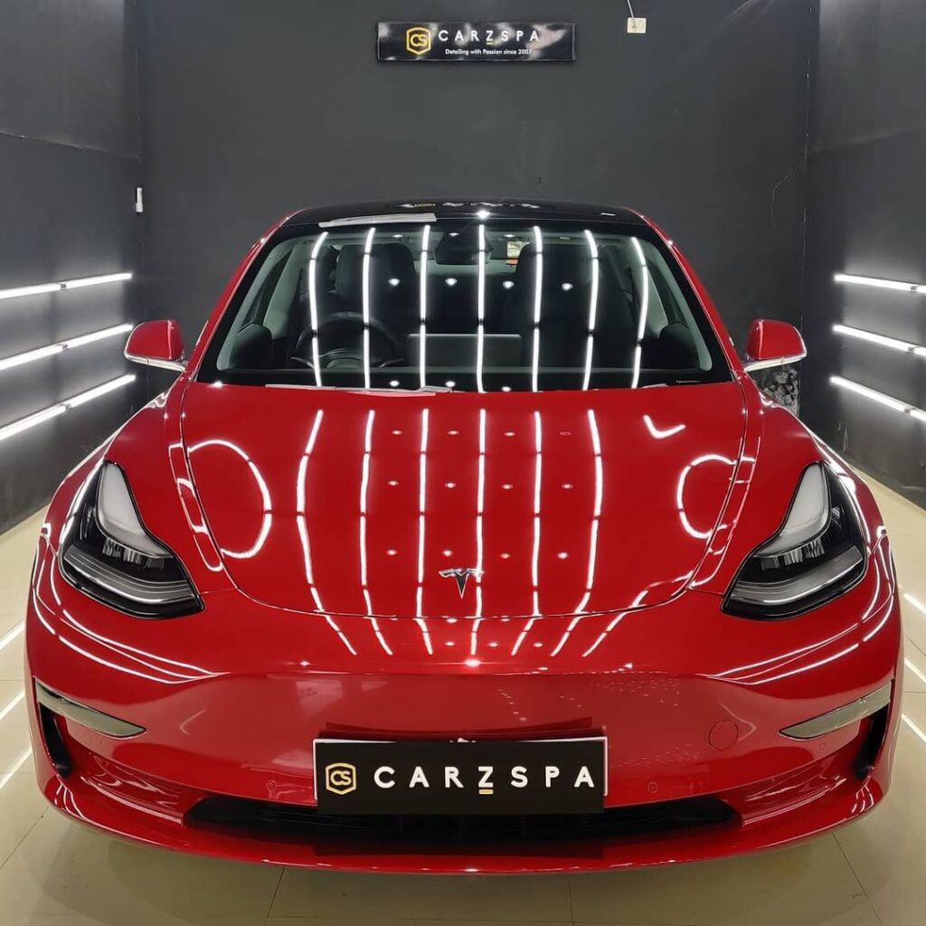 A red coloured luxury car parked inside the detailing bay