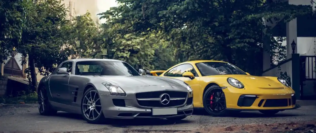 Two luxury cars parked in the background with a lot of leaves on the ground, signifying autumn