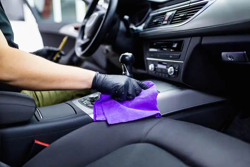 The interiors of car being cleaned with a blue microfibre towel