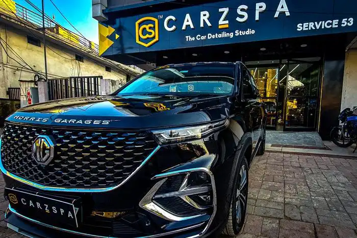 A black coloured luxury car parked outside the entrance of a car detailing studio in India