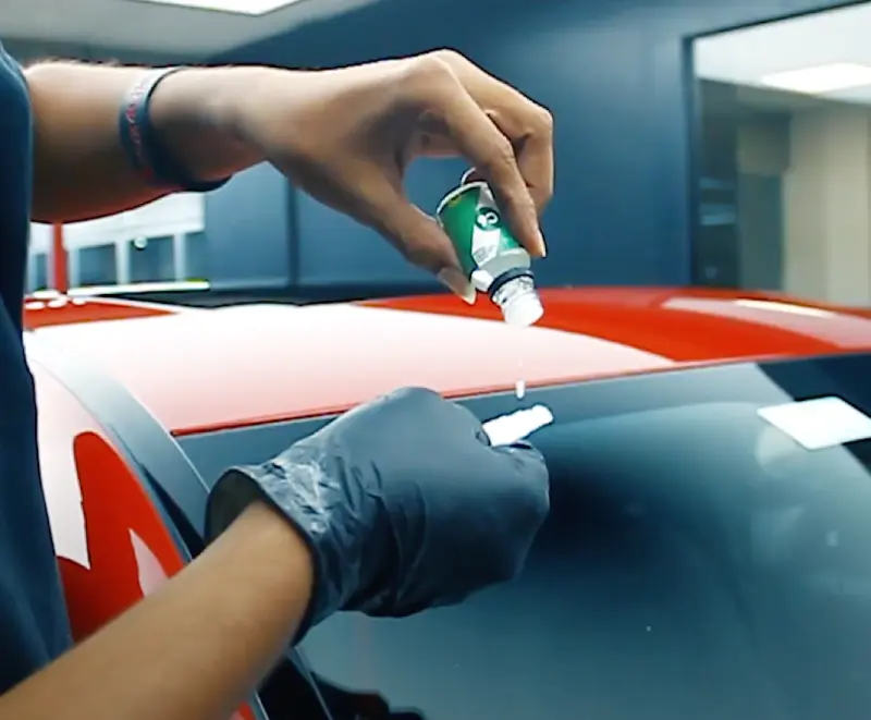 Windshield coating liquid being prepared for application on a car