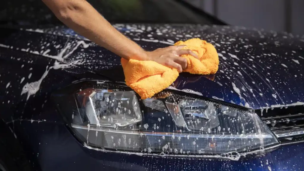 A blue car being washed at a detailing studio