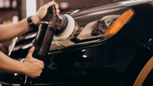 A black car being polished as a part of the car detailing job inside a detailing studio