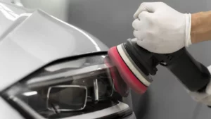 The headlamp of a white car being polished while
