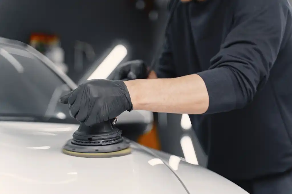 A detailer polishing the bonnet of a white car for detailing