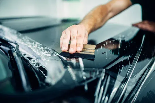 A detailer installing a clear PPF on a black car