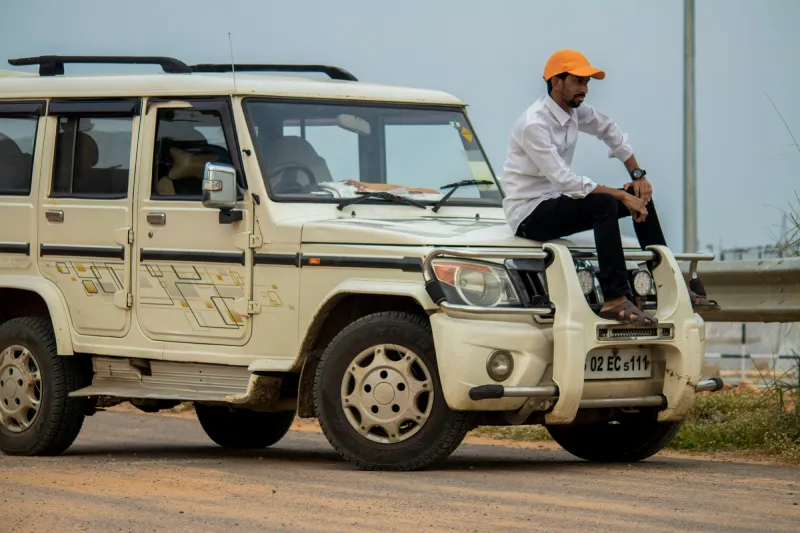 A young man sitting on the bonnet of a white coloured SUV