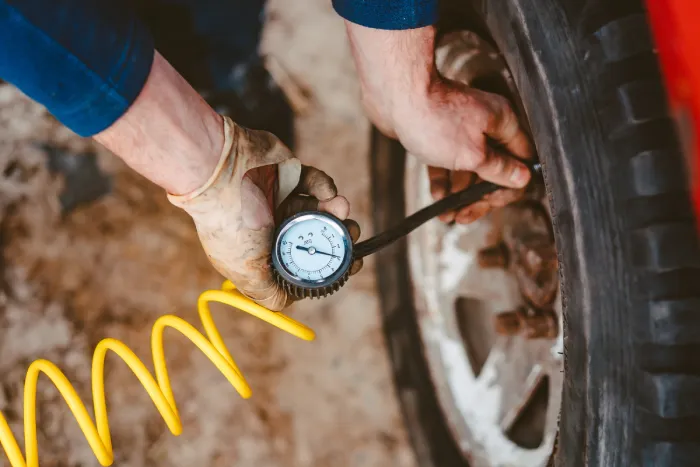 A man uses a pressure gauge to check the tyre pressure of his car