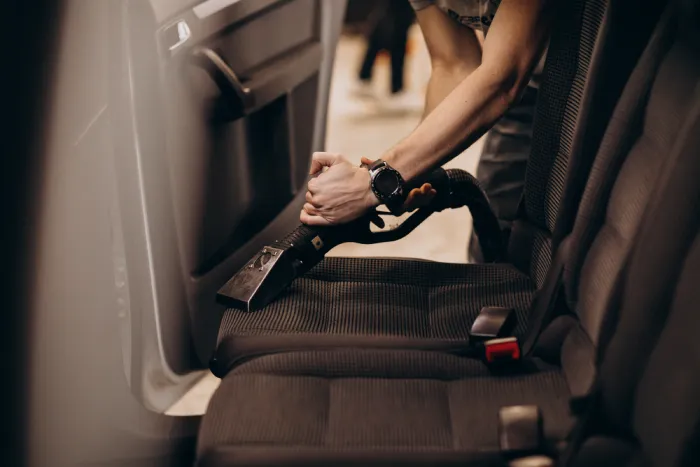 A man vacuums the seats of his car