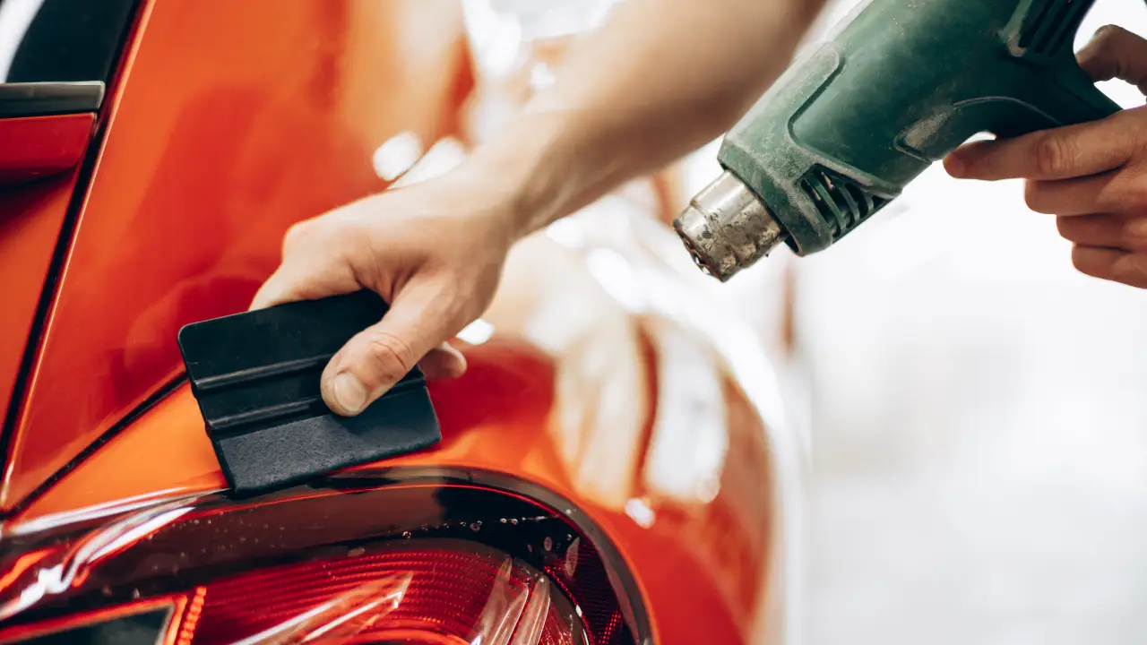 the image of a car being installed with a paint protection film using a squeegee