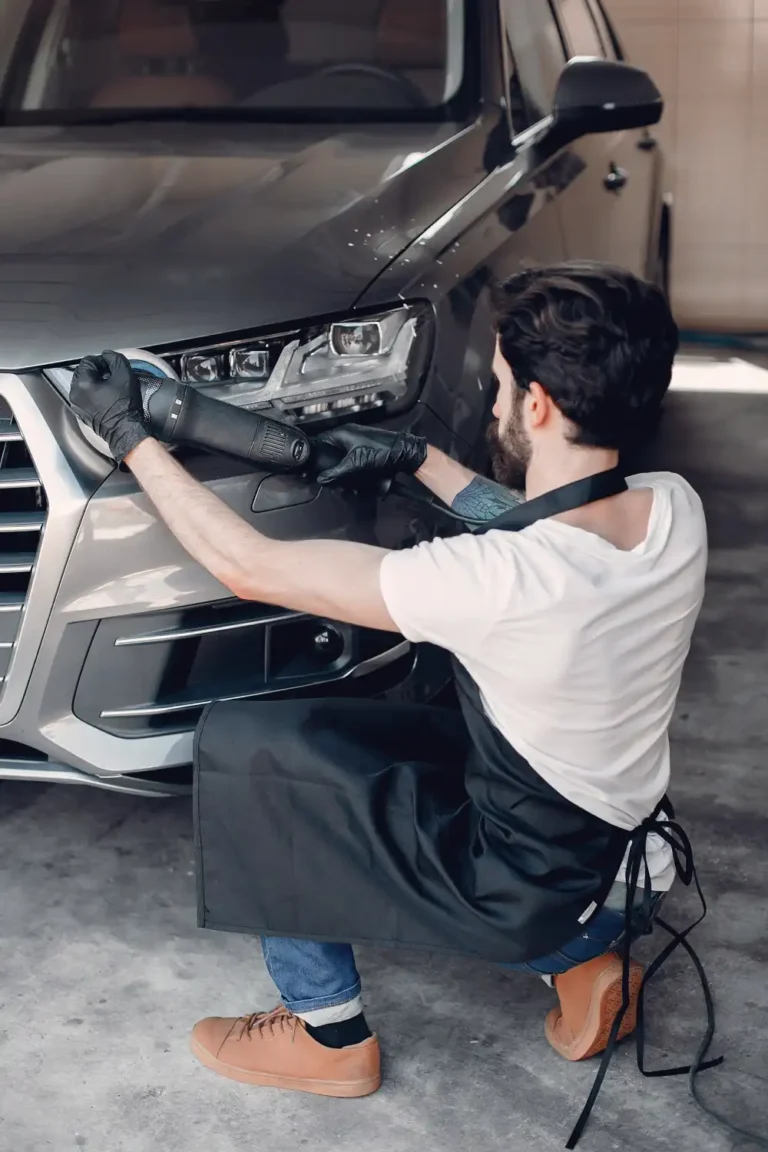 a car detailer polishes a car in a detailing studio or a garage