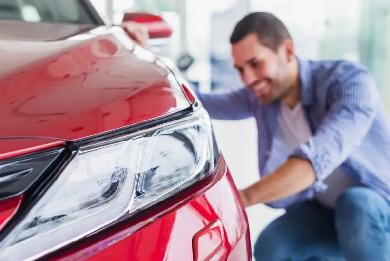 a car owner looks at his shiny new car