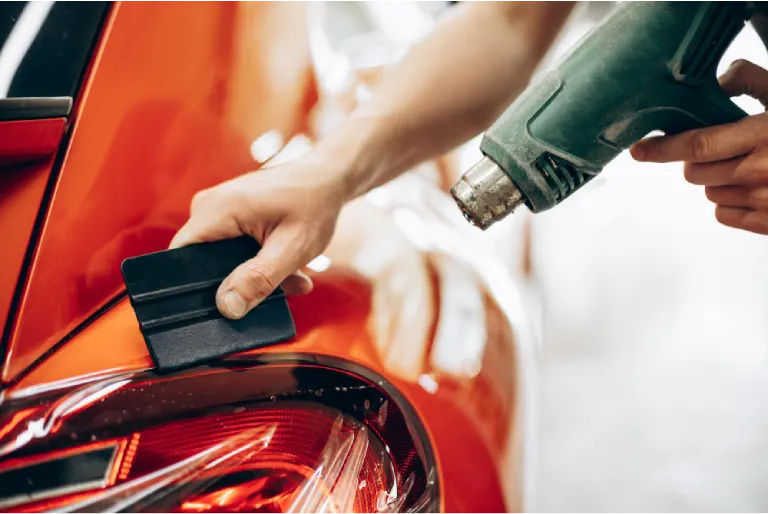 a paint protection film being installed on a red car