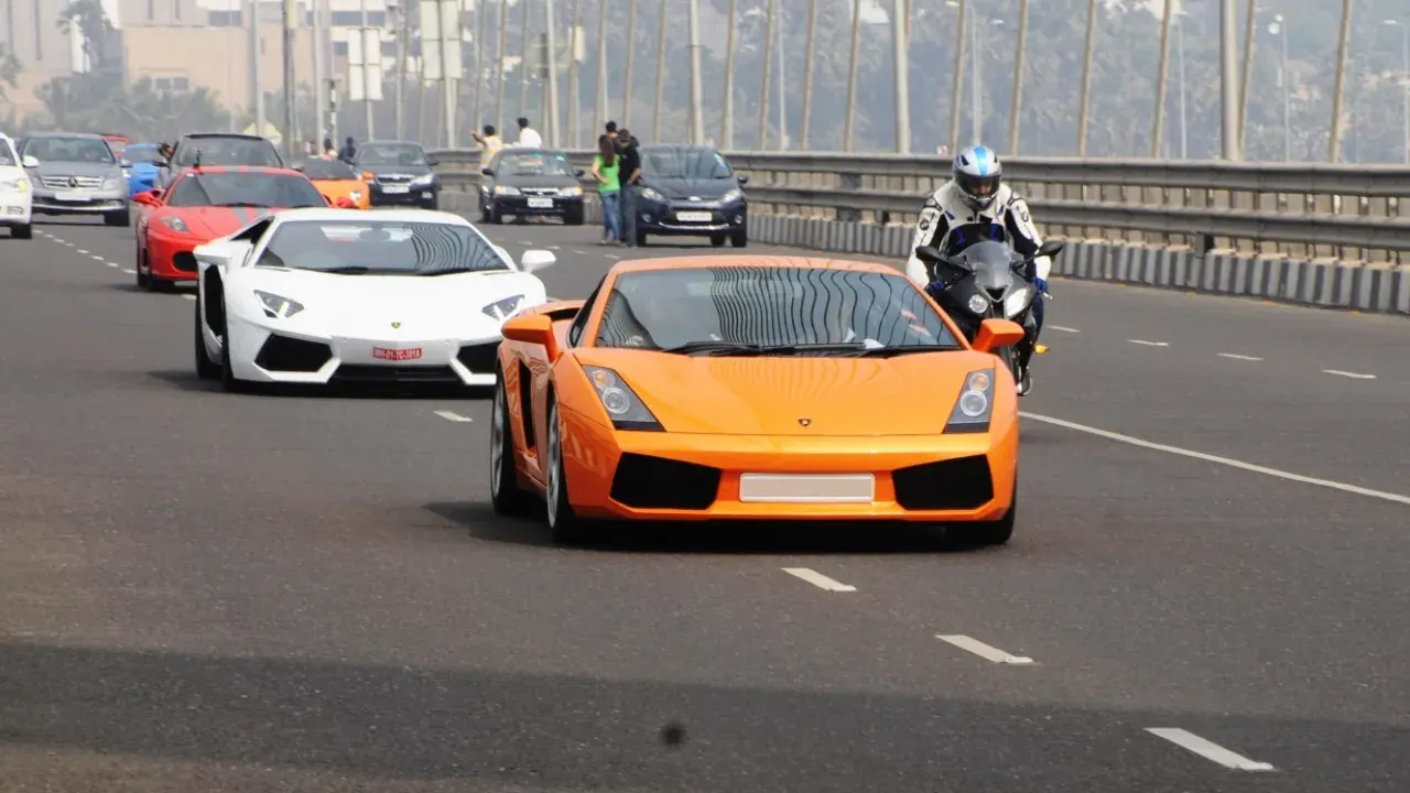 A yellow Lamborghini drives past a motorcycle on Worli Sealink