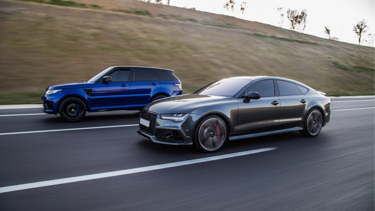 A blue SUV and a grey sports sedan driving down the highway
