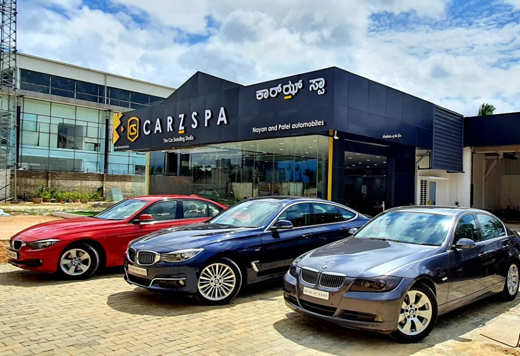 Three luxury cars parked outside a CarzSpa Detailing Studio in Bengaluru