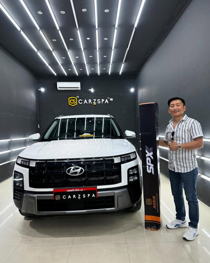 A car owner stands next to a white Audi SUV with a box of PPF