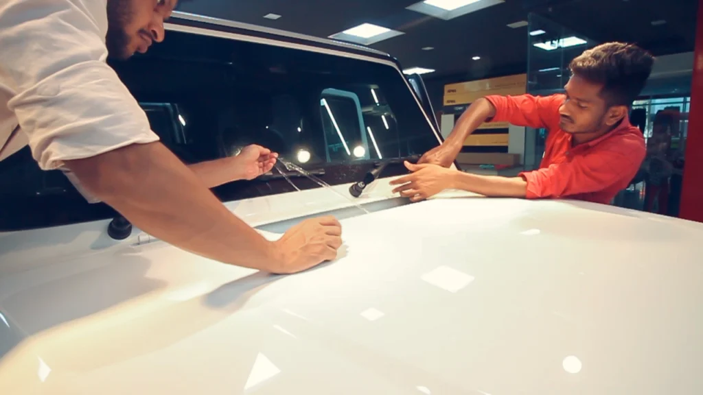 Two workers installing a PPF on a white coloured Mercedes G-Wagon