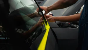 A worker applying a car window film onto a side window glass of a car