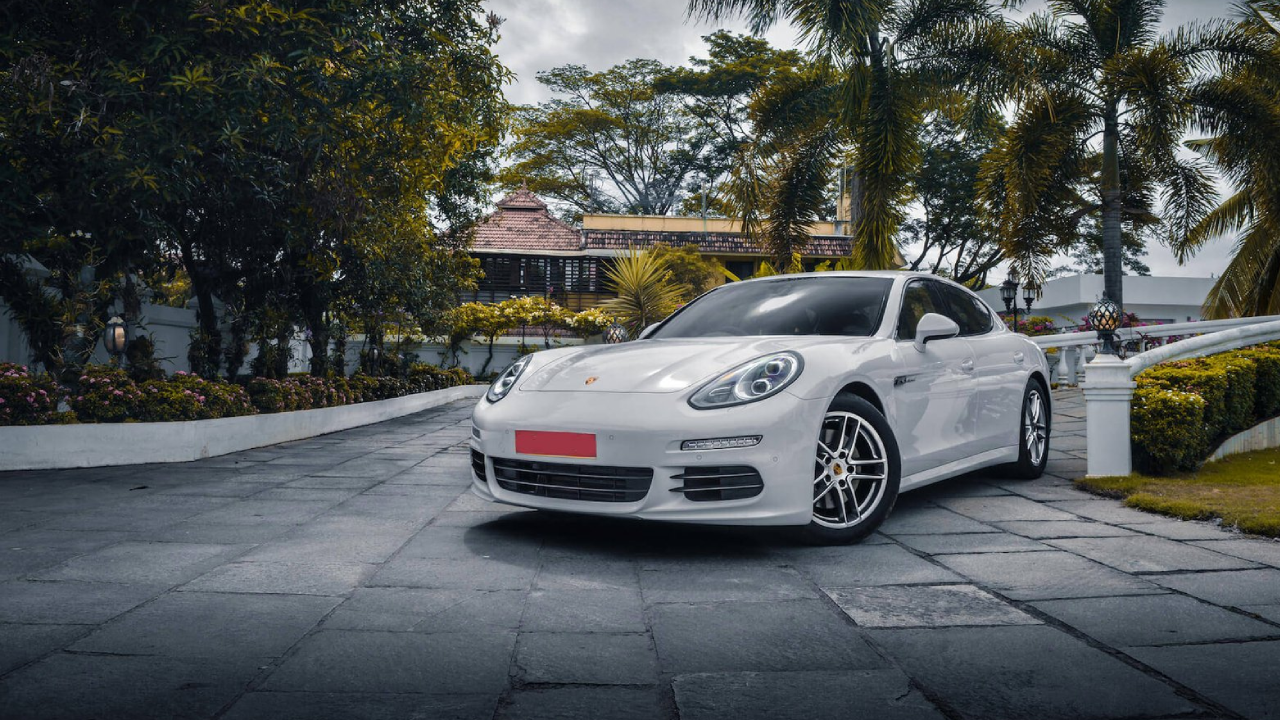 A white coloured Porsche parked in front of a mansion in Kerala