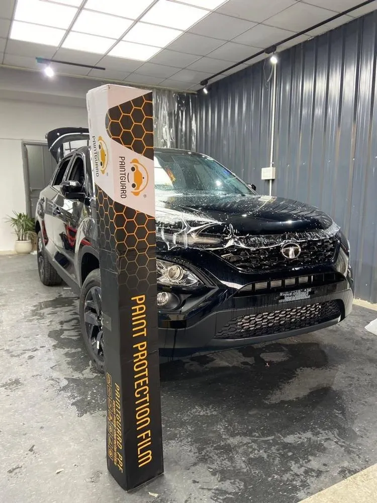 A box of paint guard PPF placed next to a black coloured SUV