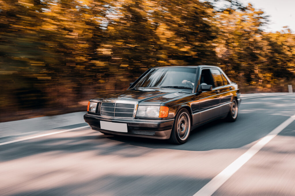 A black coloured vintage Mercedes modified car speeding through a country street