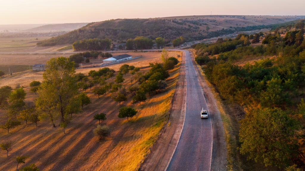 A white car driving through a winding country road somewhere in South India during sunset
