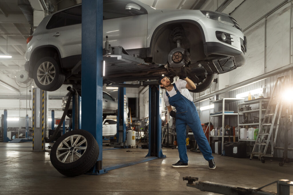 A mechanic checks the underbody of a car for suspension issues