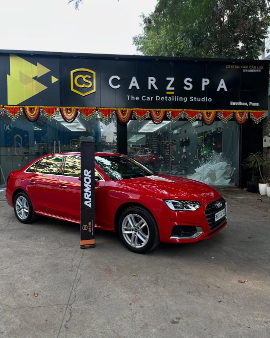 A red coloured Audi sedan parked outside a CarzSpa Detailing Studio in Pune