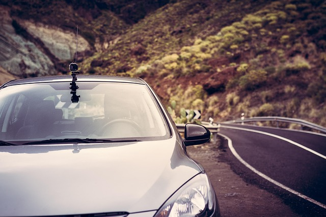 A front shot of a car with an action camera on the top, parked on the side of a mountainous road