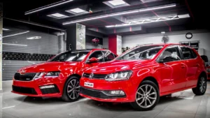 Two red coloured shiny cars parked inside a car detailing studio