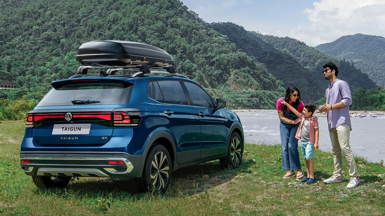 A vibrant blue Volkswagen Taigun parked at a scenic outdoor location with a South Asian family of 3 standing next to it