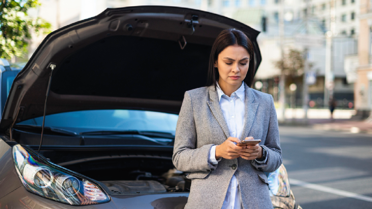 Businesswoman using a smartphone to get help for her broken-down car