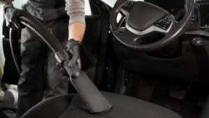 A person vacuums the interior of a car, cleaning the seats and floors thoroughly