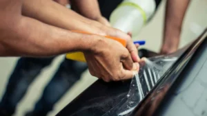 Close-up of clear Paint Protection Film (PPF) edge on a car's panel, protecting the finish.