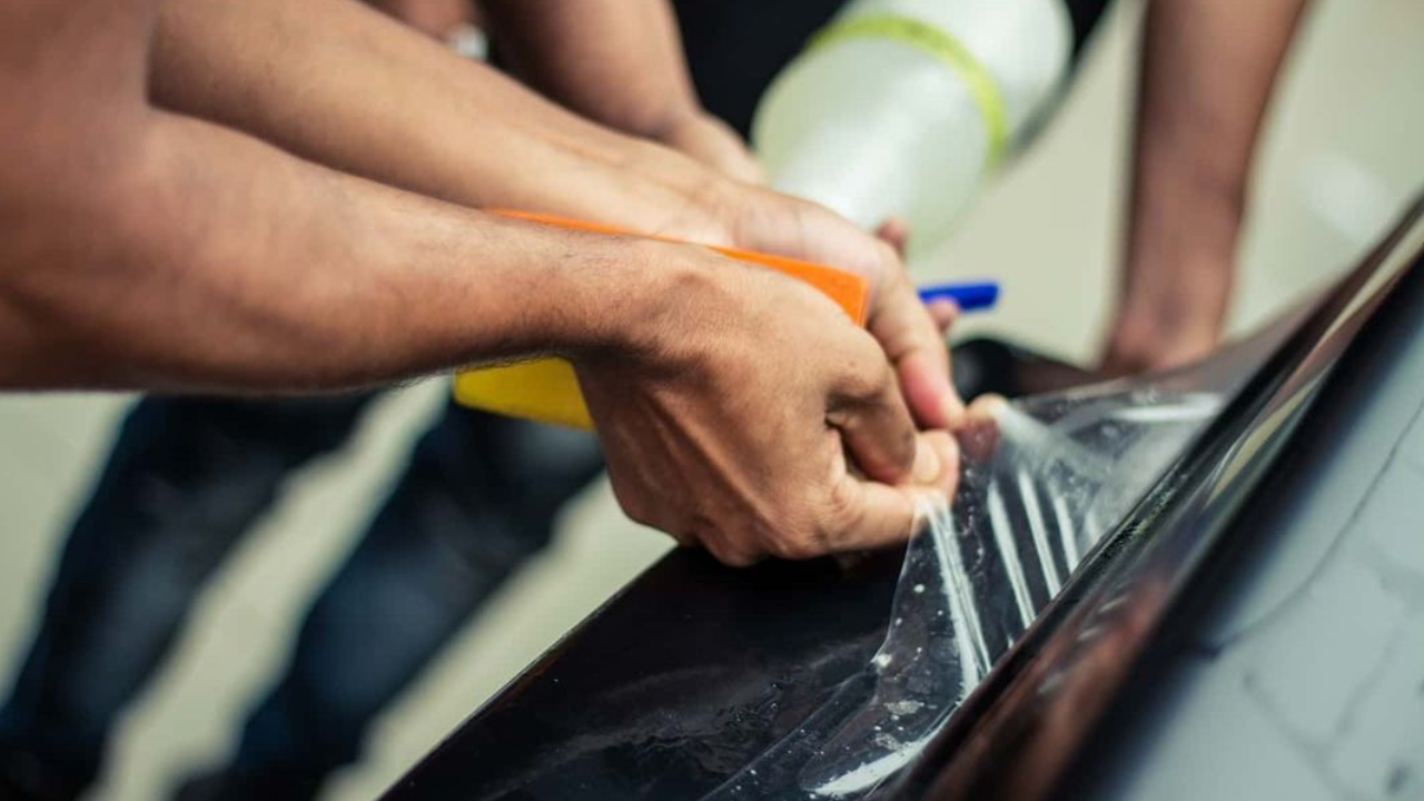 Close-up of clear Paint Protection Film (PPF) edge on a car's panel, protecting the finish.