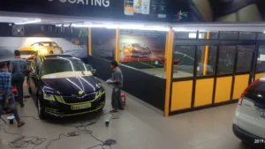 Workers working on a car inside a car detailing workshop