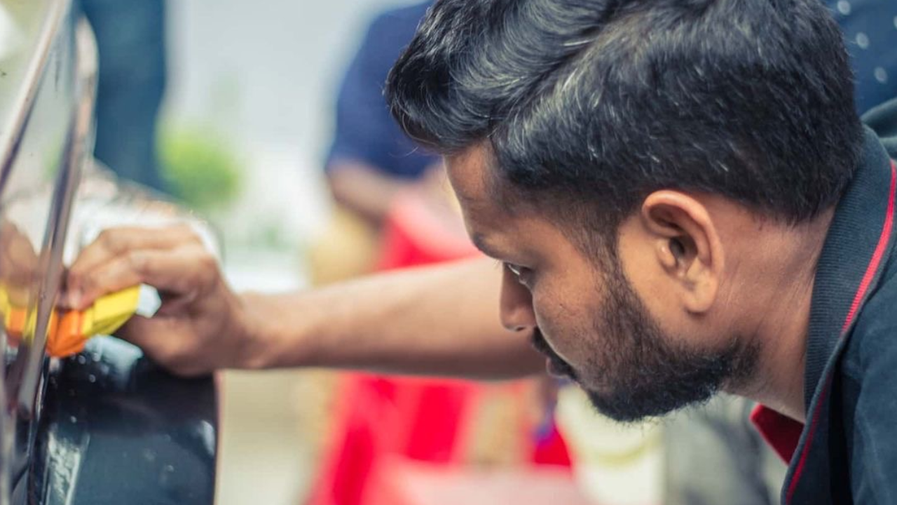 A worker applies PPF on the contours of a car