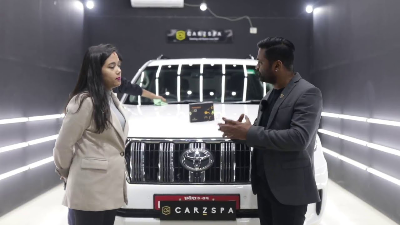 A man and a woman talking to each other in front of an SUV parked inside a workshop