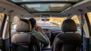 A premium SUV featuring an expansive panoramic sunroof, driving in a scenic hill station.