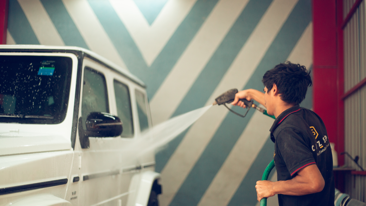 A professional detailer washes a car with paint protection film.