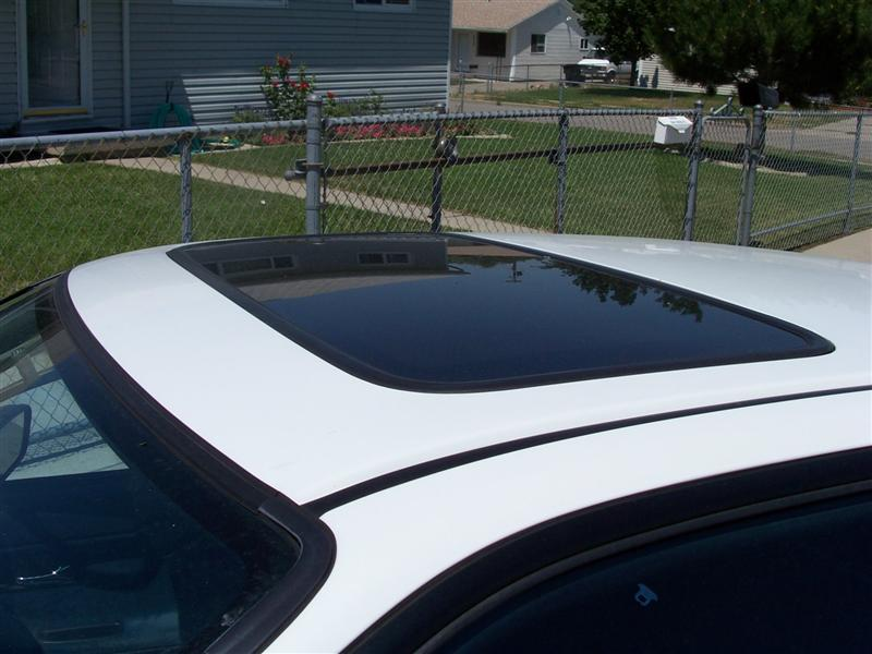 A black sliding moonroof on the top of a white car