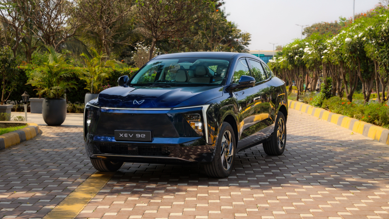A sleek, Nebula-blue Mahindra XEV 9e parked in a modern urban setting.