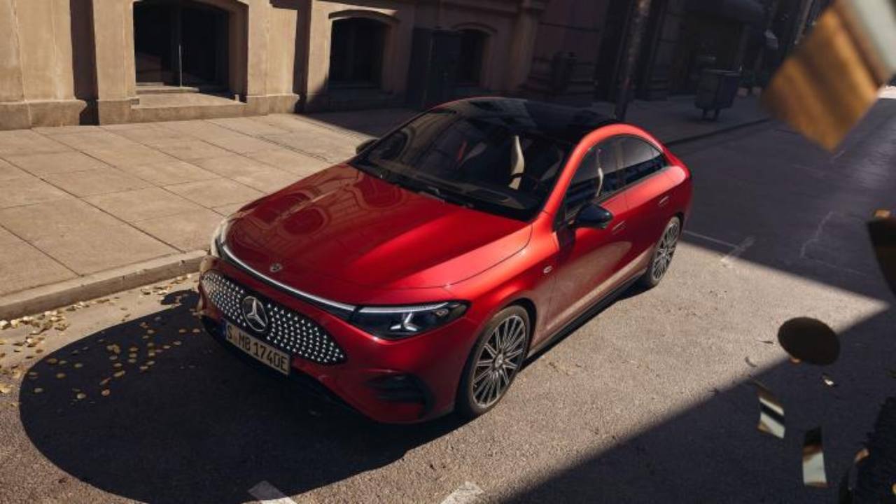 A futuristic, red Mercedes-Benz CLA Electric showing its illuminated star-pattern grille and sleek coupe silhouette on a street.