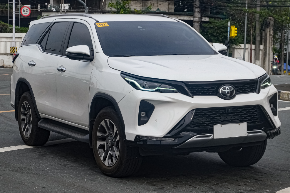 A white Toyota Fortuner parked in an open parking street