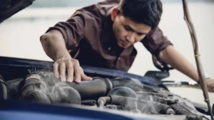 A car with its hood open on a bright sunny day in India, showing the engine bay.